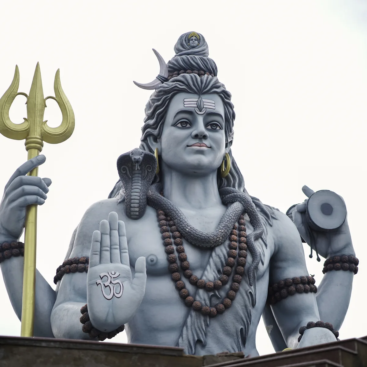 A statue of Shiva with trident, damaru and rudraksha, his hand raised in blessing